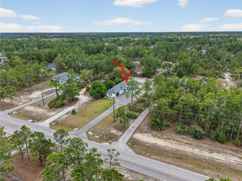 Aerial property capture featuring a single-story residence with a dark roof and white exterior