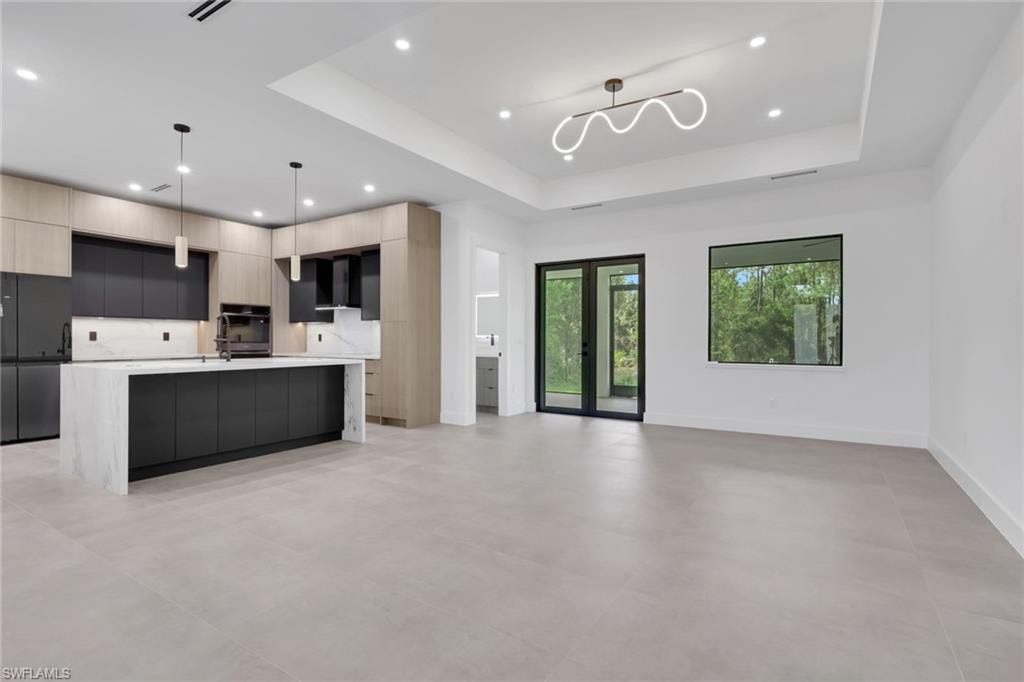 Open concept living space featuring a contemporary kitchen with a waterfall island, two-tone cabinetry, and integrated appliances