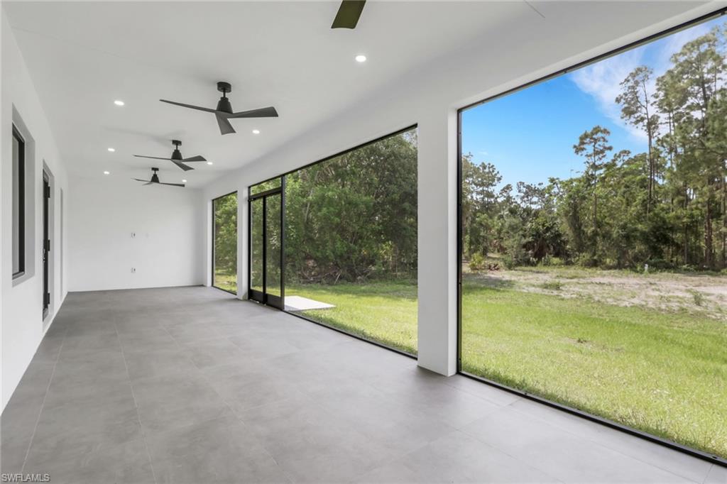 Spacious screened lanai featuring large format tile flooring, recessed lighting, and multiple ceiling fans