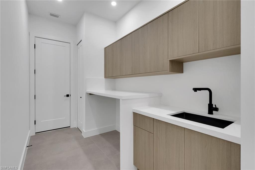 Laundry area featuring light wood-finish cabinetry and white countertops
