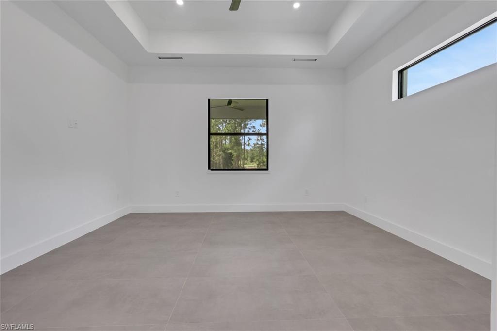 Spacious interior featuring neutral tile flooring, white walls, and a tray ceiling with recessed lighting