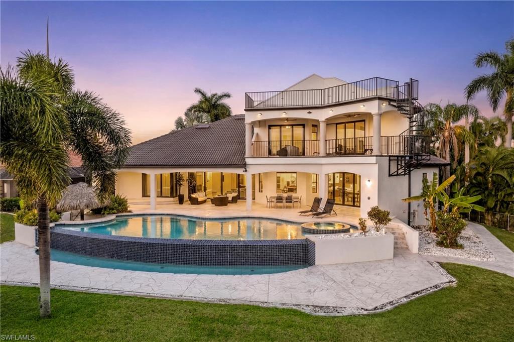 Back of property featuring a patio area, a balcony, stucco siding, an outdoor living space, and a pool with connected hot tub