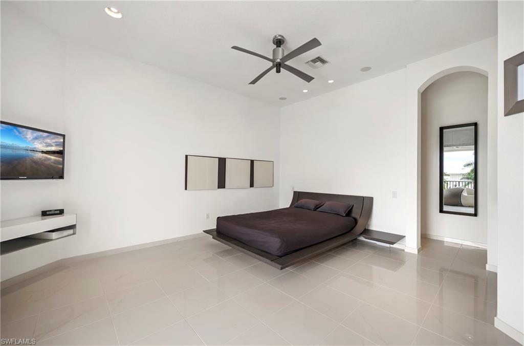 Guest Bedroom featuring light tile patterned floors, arched walkways, ceiling fan, and recessed lighting. Offering canal views and access to large balcony