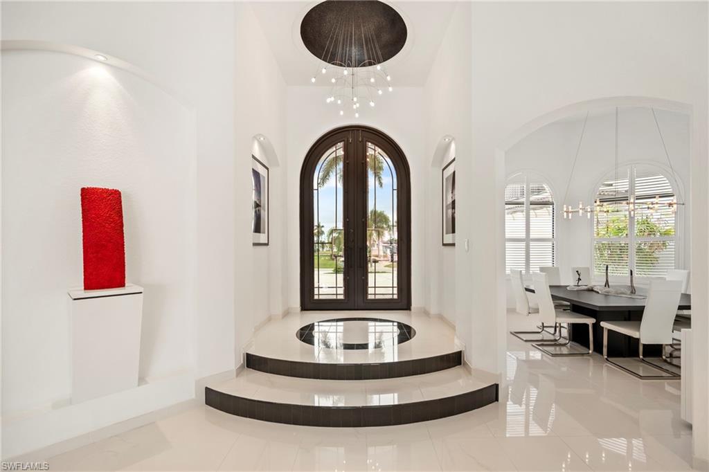 Foyer entrance with french doors, arched walkways, a chandelier, and a high ceiling