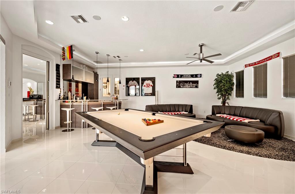 Game room with billiards, a raised ceiling, a ceiling fan, recessed lighting, and arched walkways