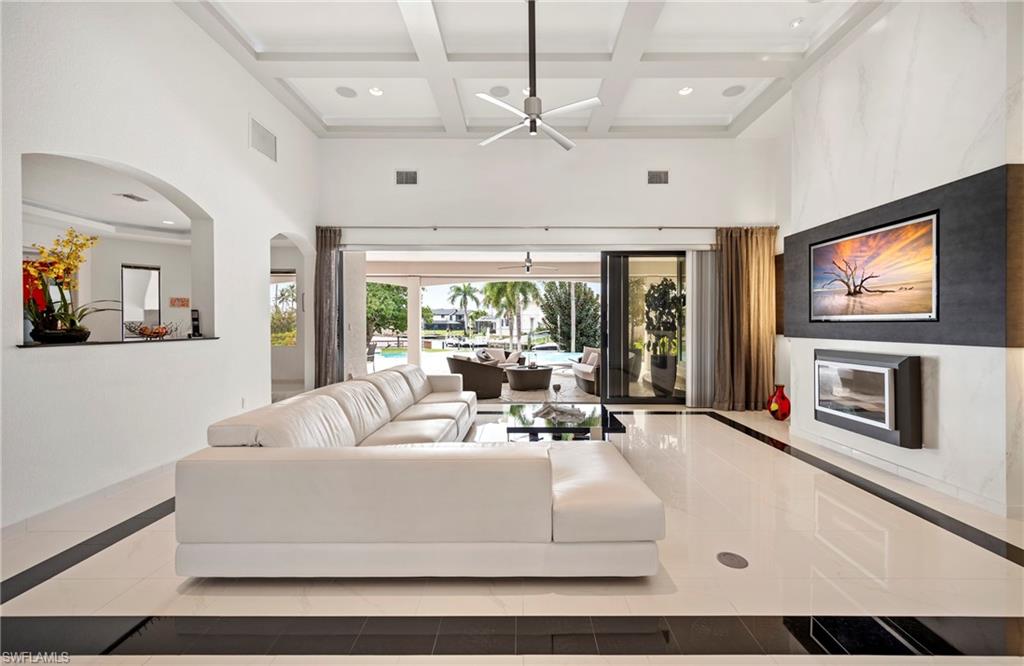 Tiled living room with inlaid floor details, coffered ceiling, recessed lighting, arched walkways, and ceiling fan