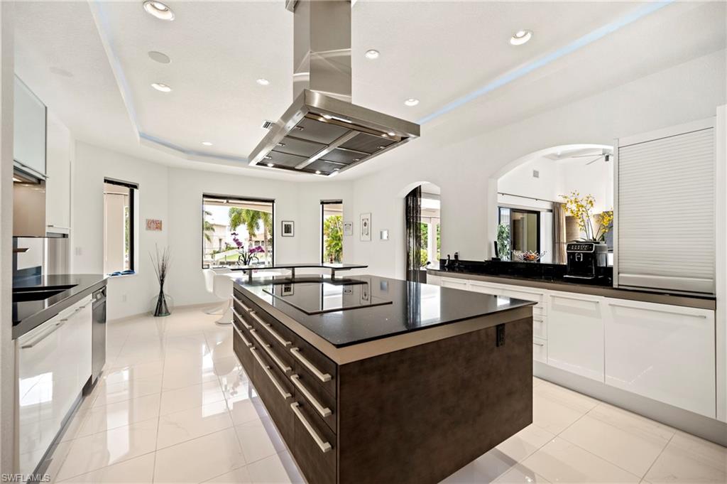 Kitchen featuring island range hood, modern cabinets, a center island, arched walkways, and recessed lighting