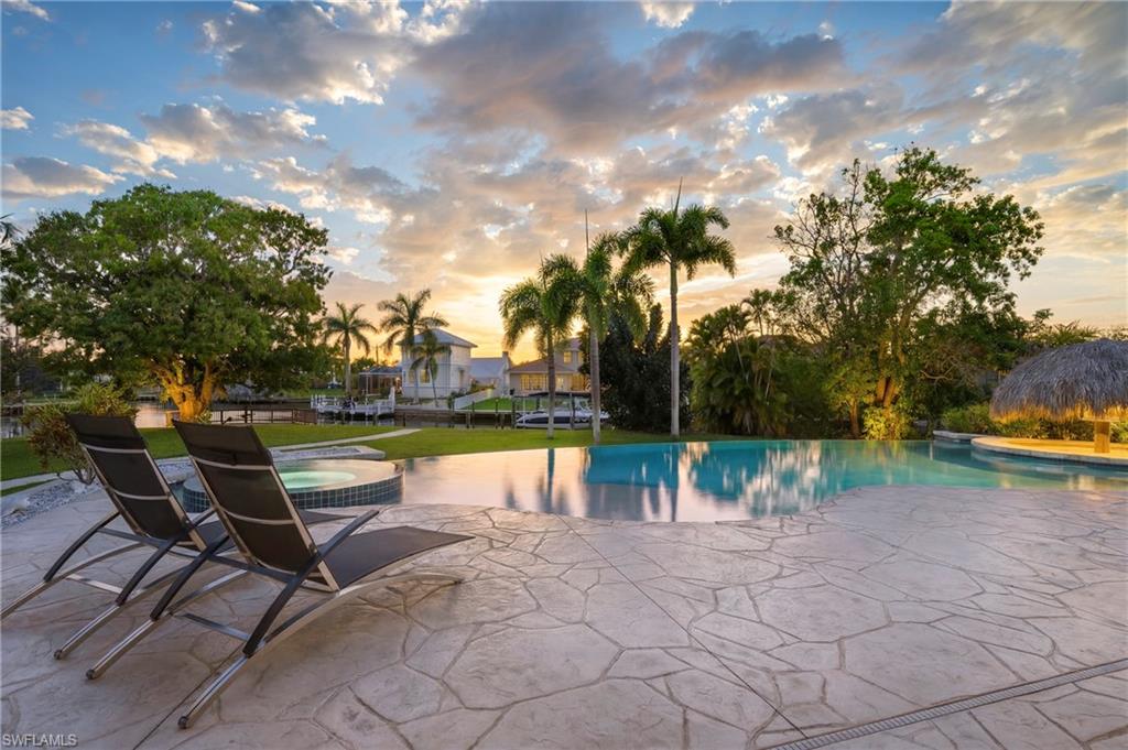 Pool at dusk featuring an in-ground hot tub, a patio, and an outdoor pool