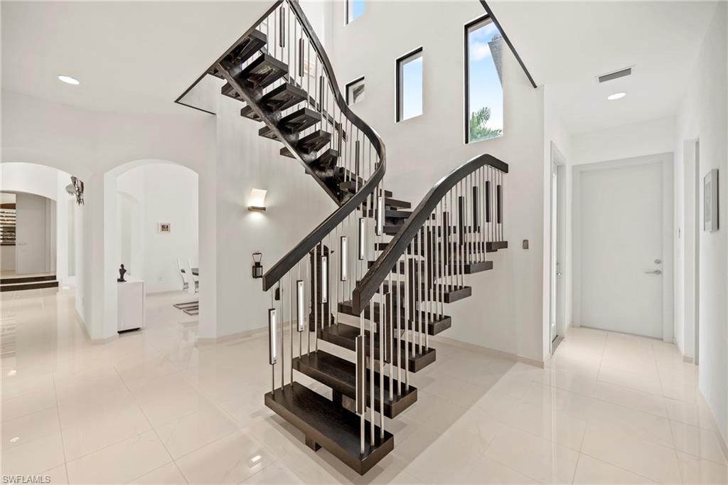 Stairs with arched walkways, recessed lighting, a high ceiling, and tile patterned flooring