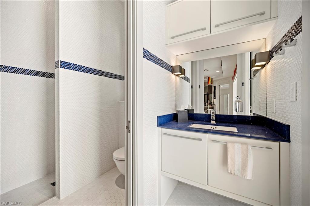 Full Bathroom accessible form the pool and outdoor area, featuring vanity, tiled shower, and light tile patterned flooring
