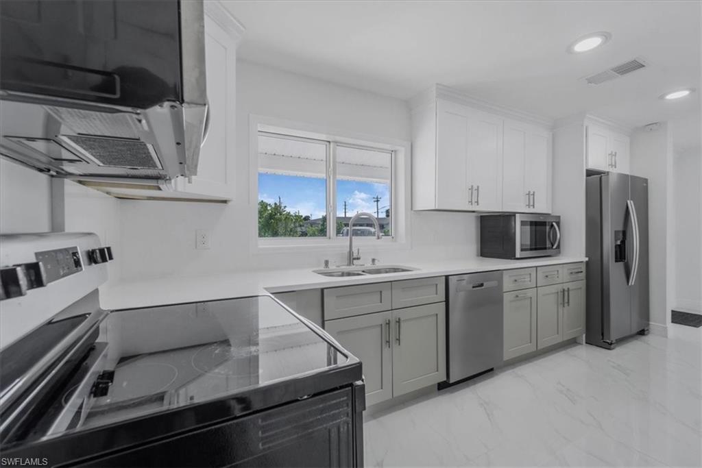 Dual tone kitchen with stainless steel appliances, extractor fan, dual tone cabinets, light marble finish flooring, and recessed lighting