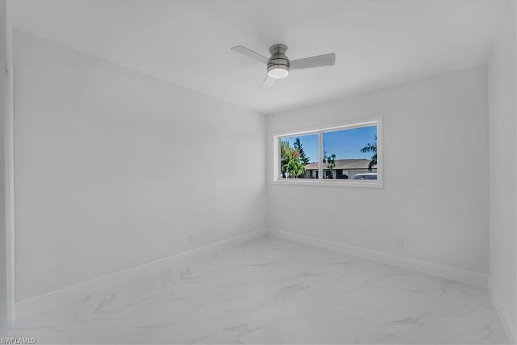 Empty room featuring light marble finish flooring and a ceiling fan