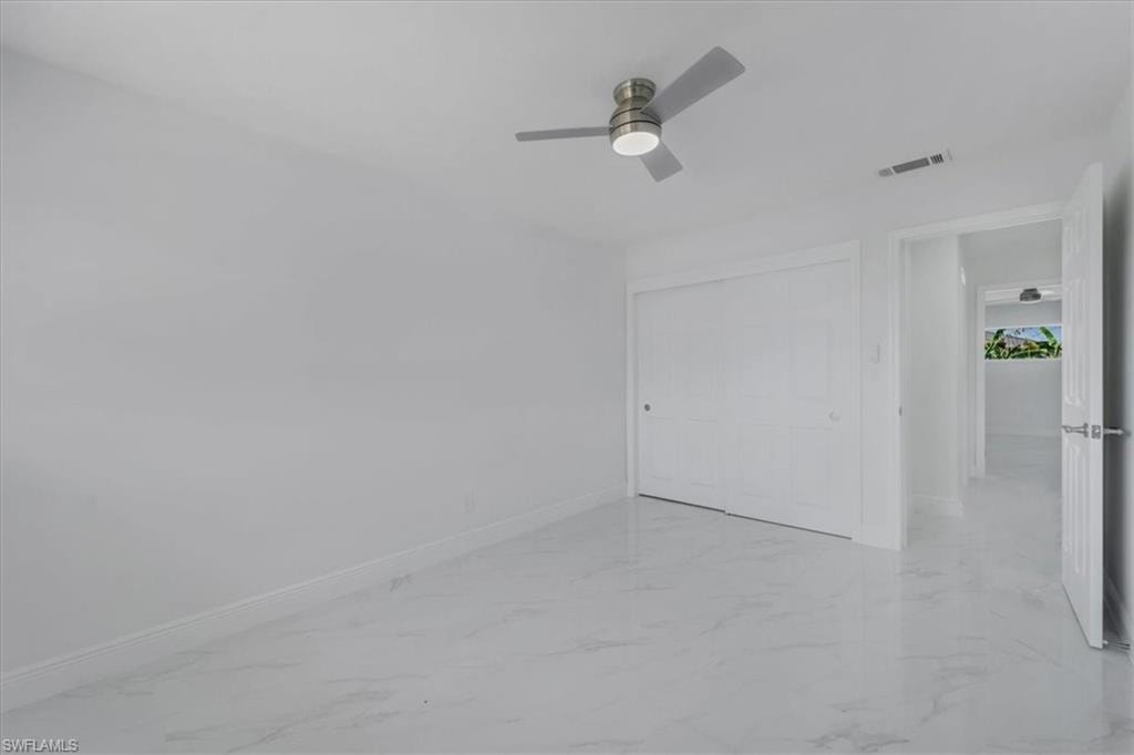 Unfurnished bedroom with light marble finish floors, a closet, and a ceiling fan