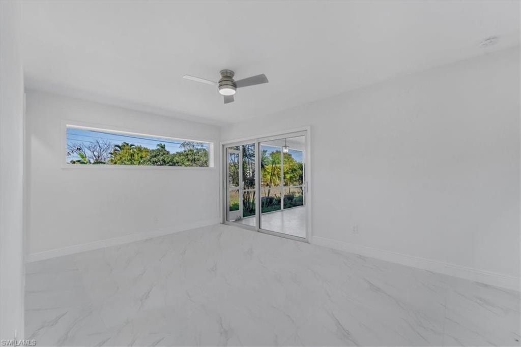 Spare room with ceiling fan and light marble finish floors