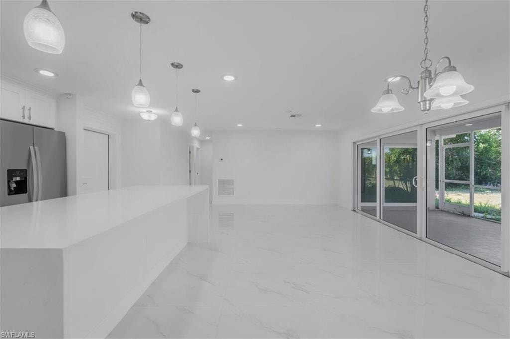 Kitchen with stainless steel refrigerator with ice dispenser, white cabinets, light stone countertops, open floor plan, and light marble finish floors