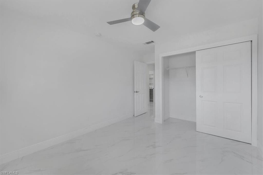 Unfurnished bedroom featuring light marble finish flooring, a closet, and ceiling fan