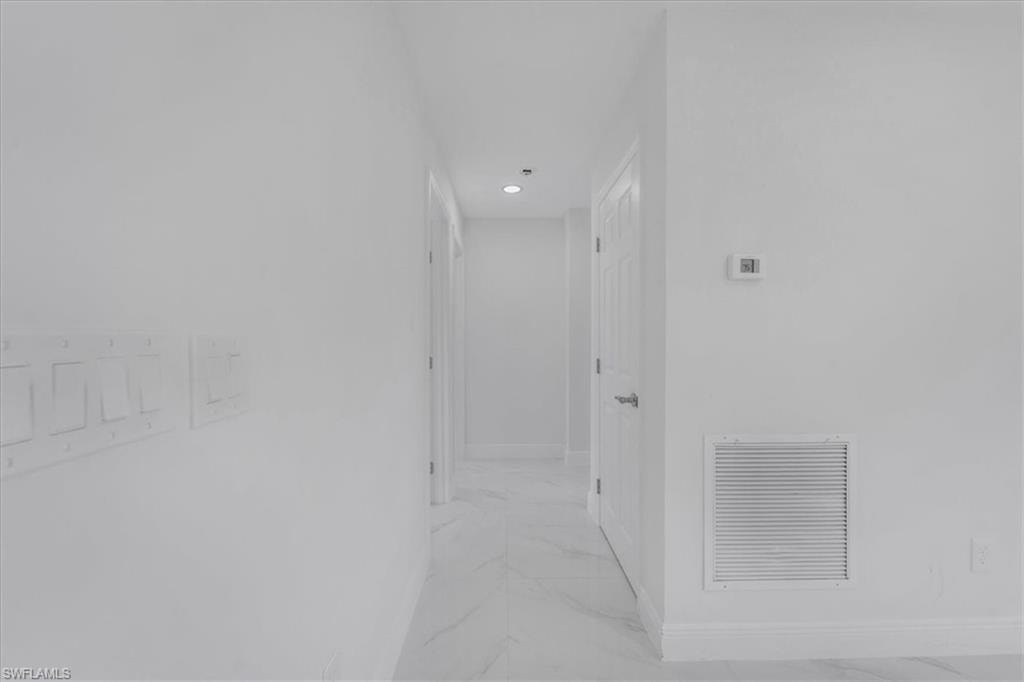 Hall featuring baseboards and light marble finish flooring