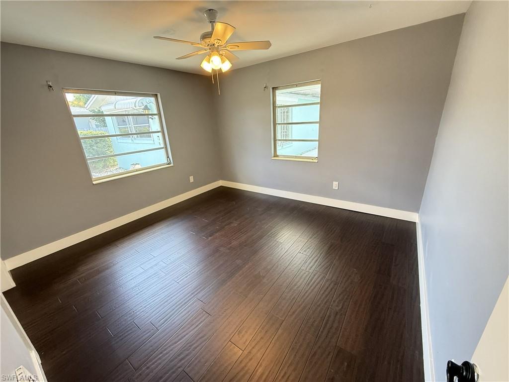 Empty room with dark wood finished floors and ceiling fan