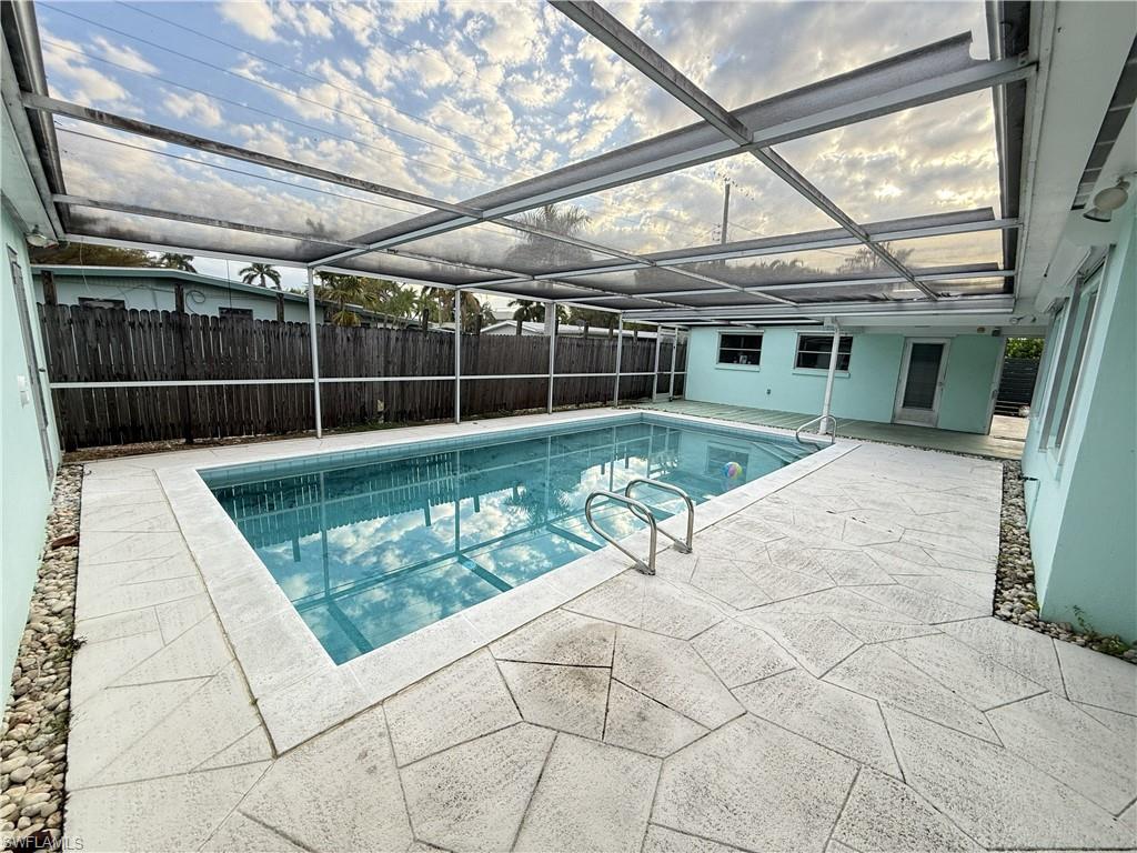 View of pool with a sunroom, patio surround, a lanai, and a fenced backyard