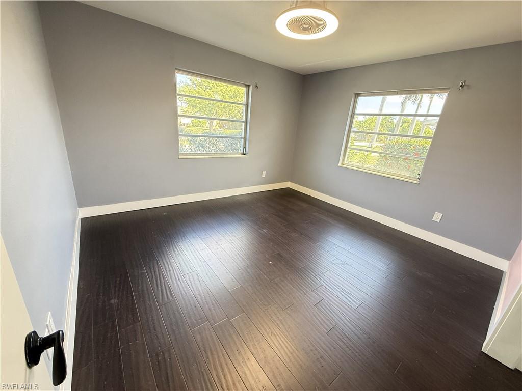 Empty room featuring plenty of natural light and dark wood-type flooring