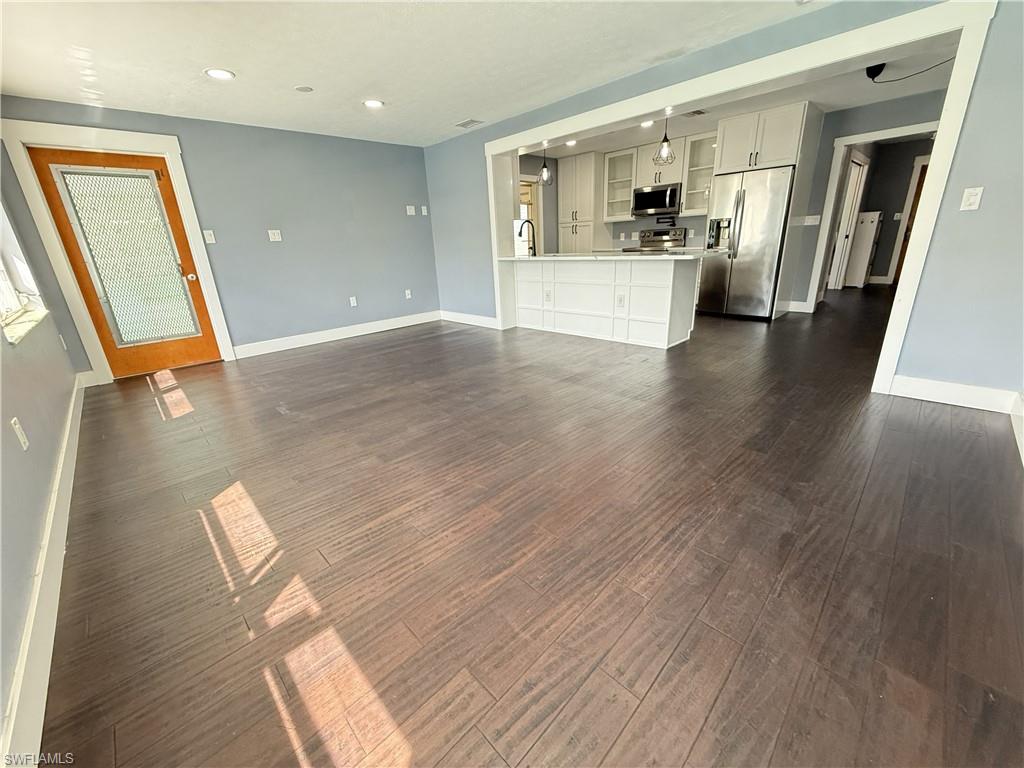 Unfurnished living room with dark wood-style flooring and recessed lighting