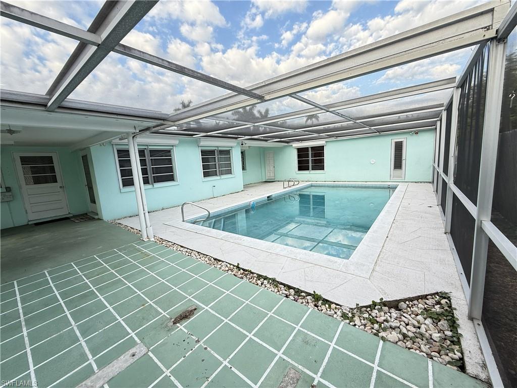 Swimming pool featuring a sunroom, a patio area, and glass enclosure