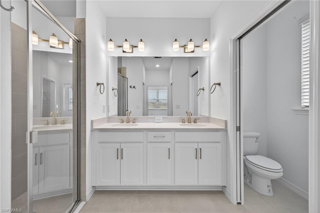 Bathroom featuring double vanity, a stall shower, and light tile patterned flooring