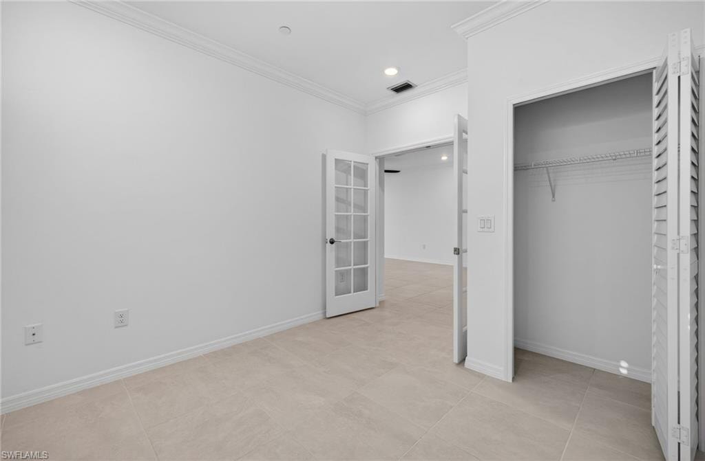 Unfurnished bedroom featuring ornamental molding, a closet, recessed lighting, and french doors