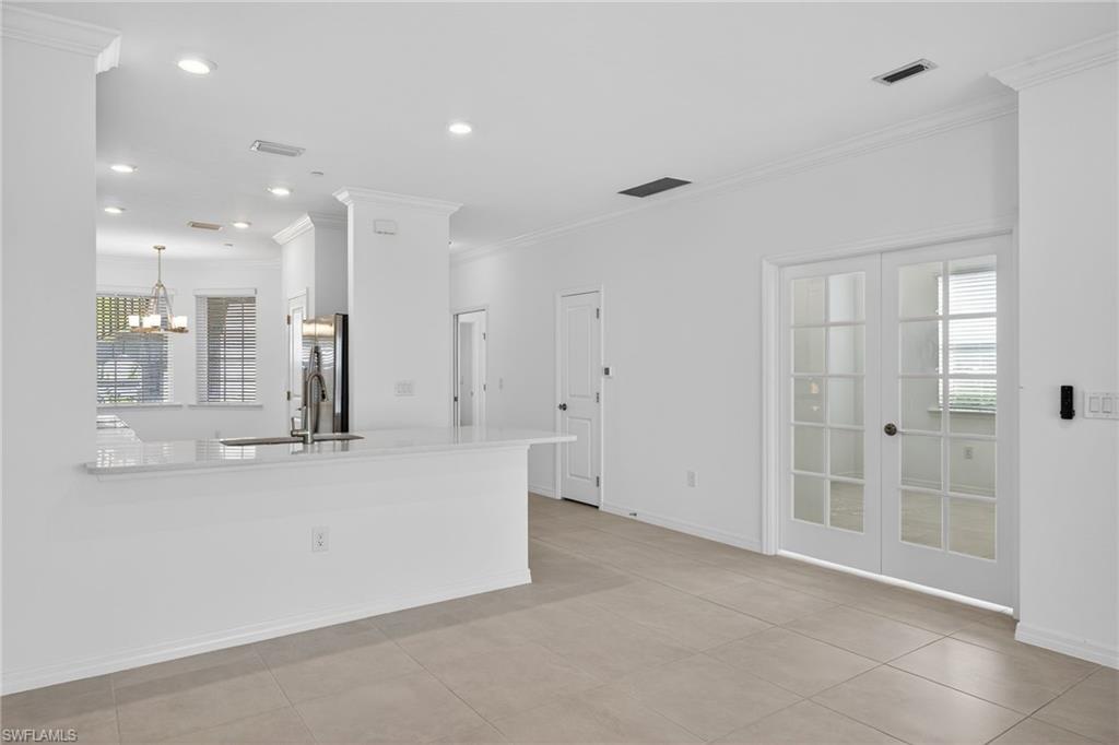 Kitchen with french doors, crown molding, a peninsula, light stone countertops, and freestanding refrigerator