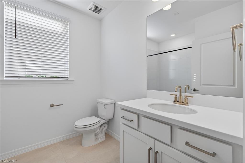 Bathroom with vanity, light tile patterned floors, and a shower