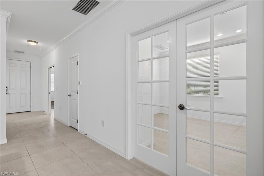 Hall with french doors, ornamental molding, and light tile patterned flooring