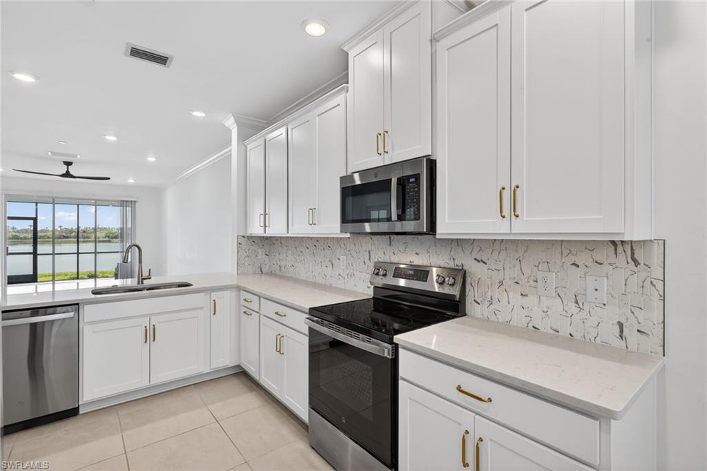 Kitchen with stainless steel appliances, white cabinets, decorative backsplash, ceiling fan, and light tile patterned floors