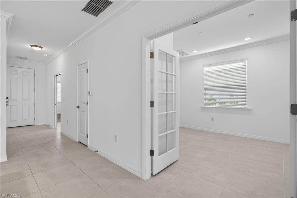 Corridor featuring ornamental molding and light tile patterned flooring