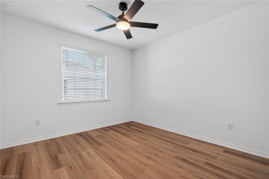 Unfurnished room featuring light wood finished floors, a ceiling fan, and a smoke detector