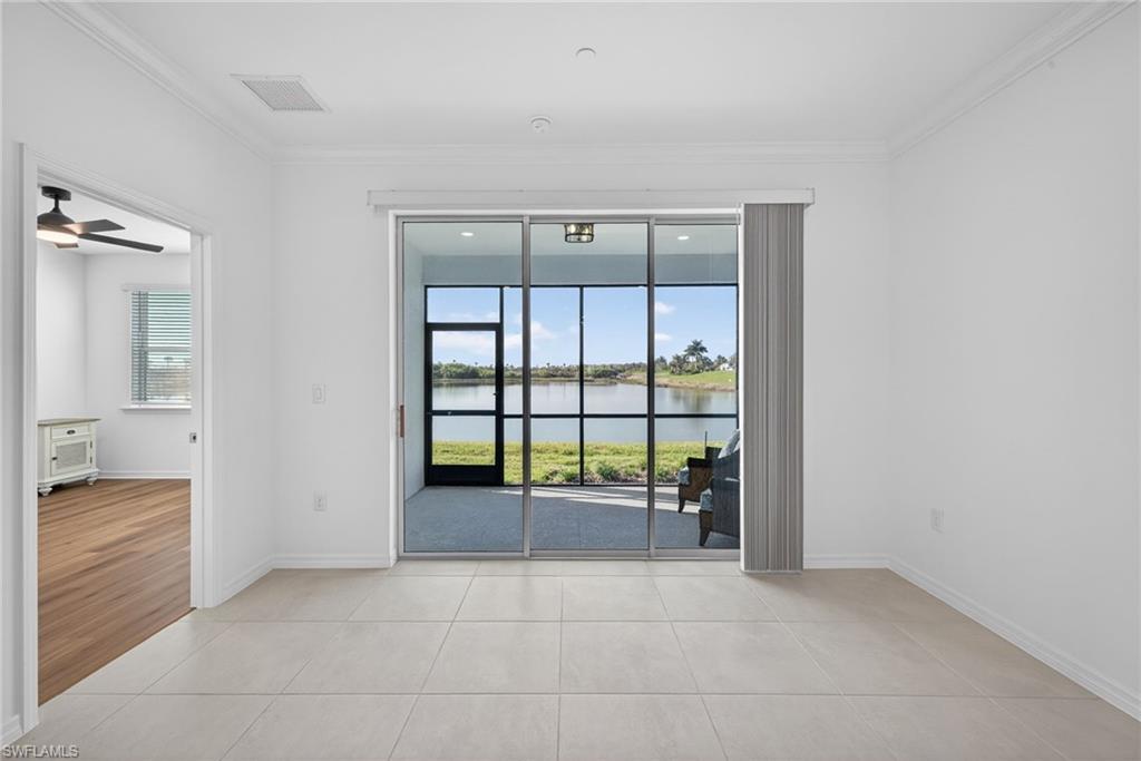 Spare room with a water view, crown molding, a ceiling fan, and light tile patterned floors