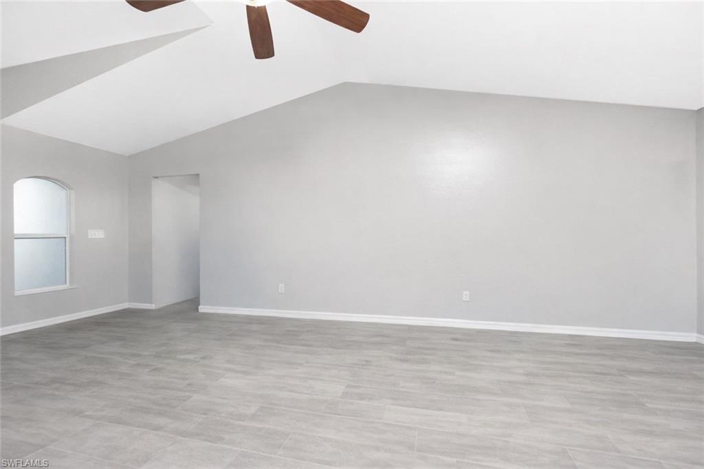 Empty room featuring lofted ceiling and ceiling fan