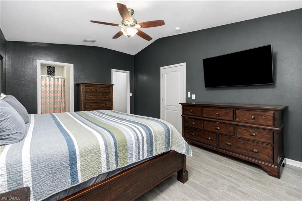 Bedroom featuring ceiling fan, lofted ceiling, and wood tiled floors