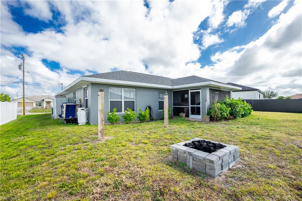 Back of property with stucco siding, a fire pit, a sunroom, and roof with shingles