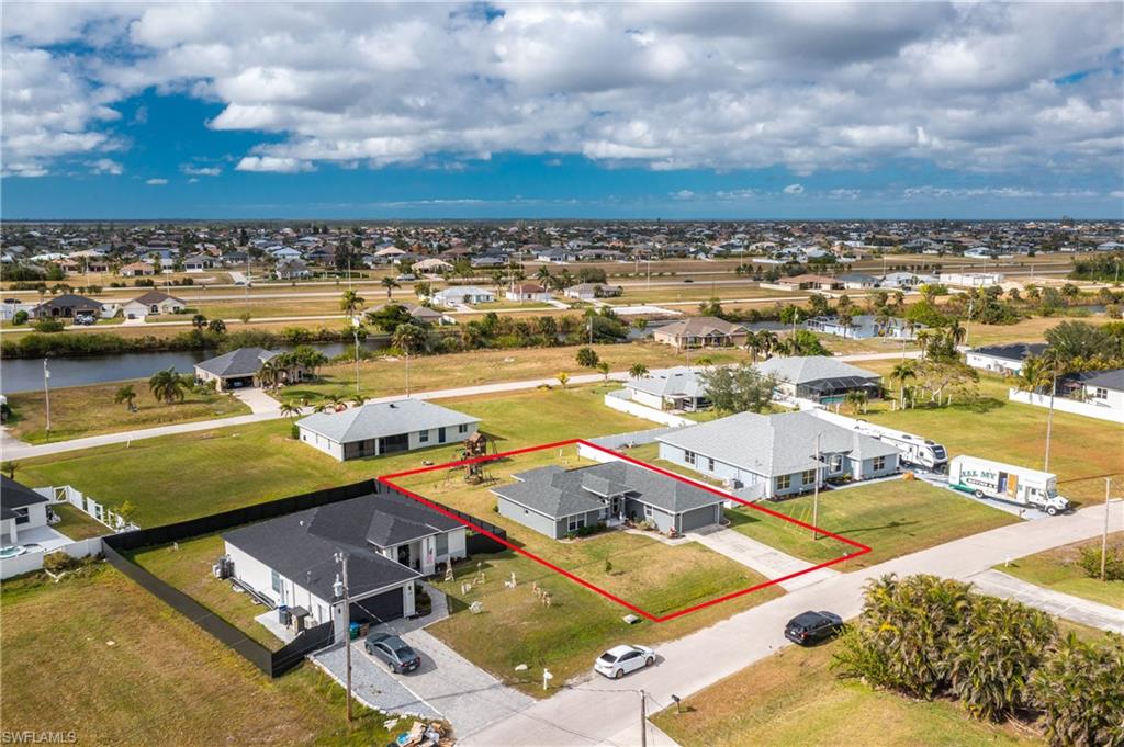 Aerial view of residential area with property boundaries highlighted and a large body of water