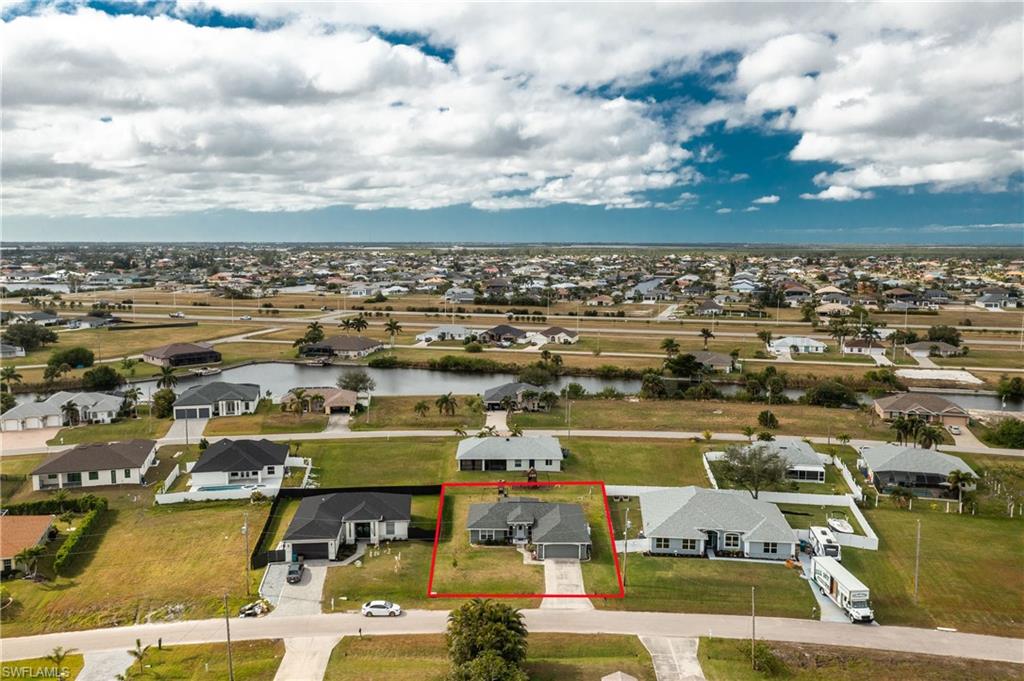 Aerial perspective of suburban area featuring property boundaries highlighted and a nearby body of water