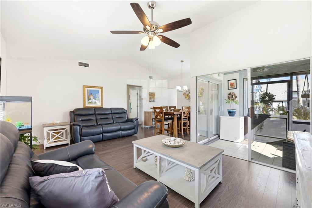 Living room with healthy amount of natural light, a ceiling fan, wood finished floors, and vaulted ceiling