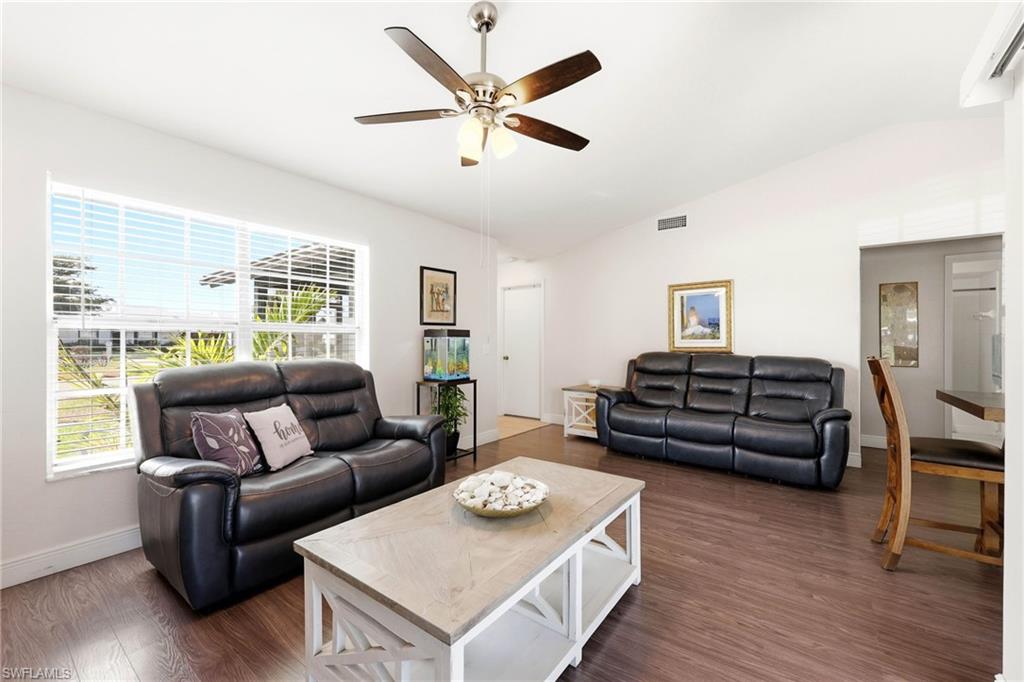 Living area with vaulted ceiling, dark wood-type flooring, and a ceiling fan