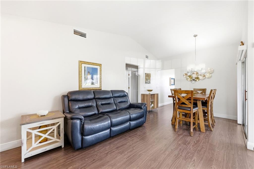 Living room with wood finished floors, a chandelier, and vaulted ceiling