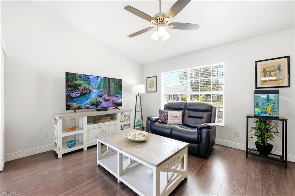 Living area with dark wood-type flooring, vaulted ceiling, and a ceiling fan