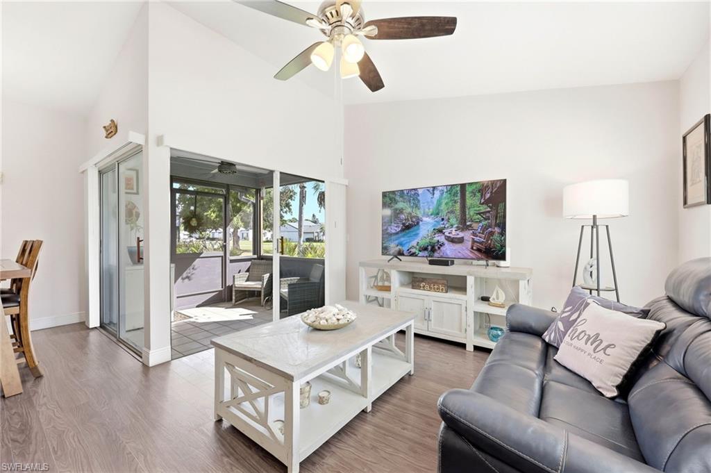 Living room featuring a ceiling fan, wood finished floors, and lofted ceiling