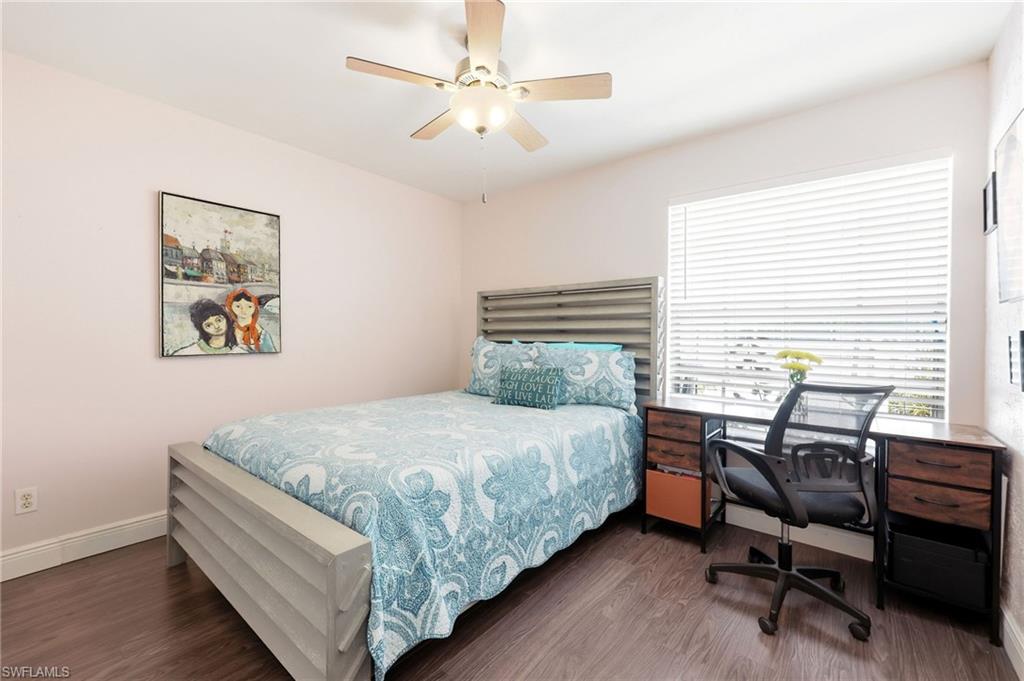 Bedroom featuring dark wood-style flooring, a ceiling fan, and an office area