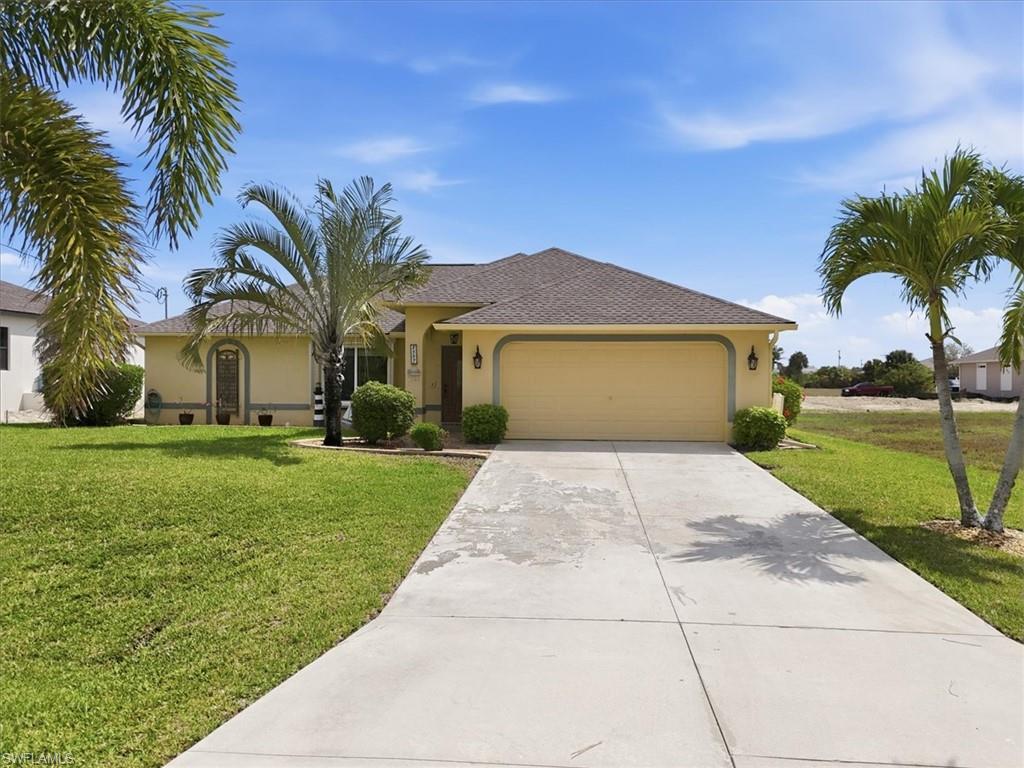 Ranch-style home with a front yard, a garage, driveway, and stucco siding