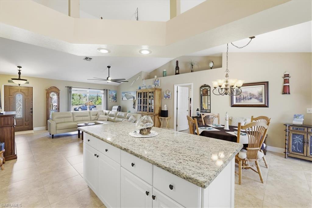 Kitchen with a center island, white cabinets, light stone countertops, a ceiling fan, and open floor plan