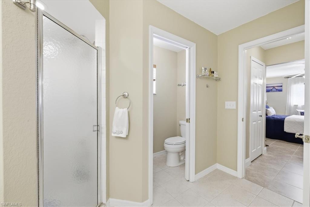 Ensuite bathroom featuring a stall shower and light tile patterned flooring