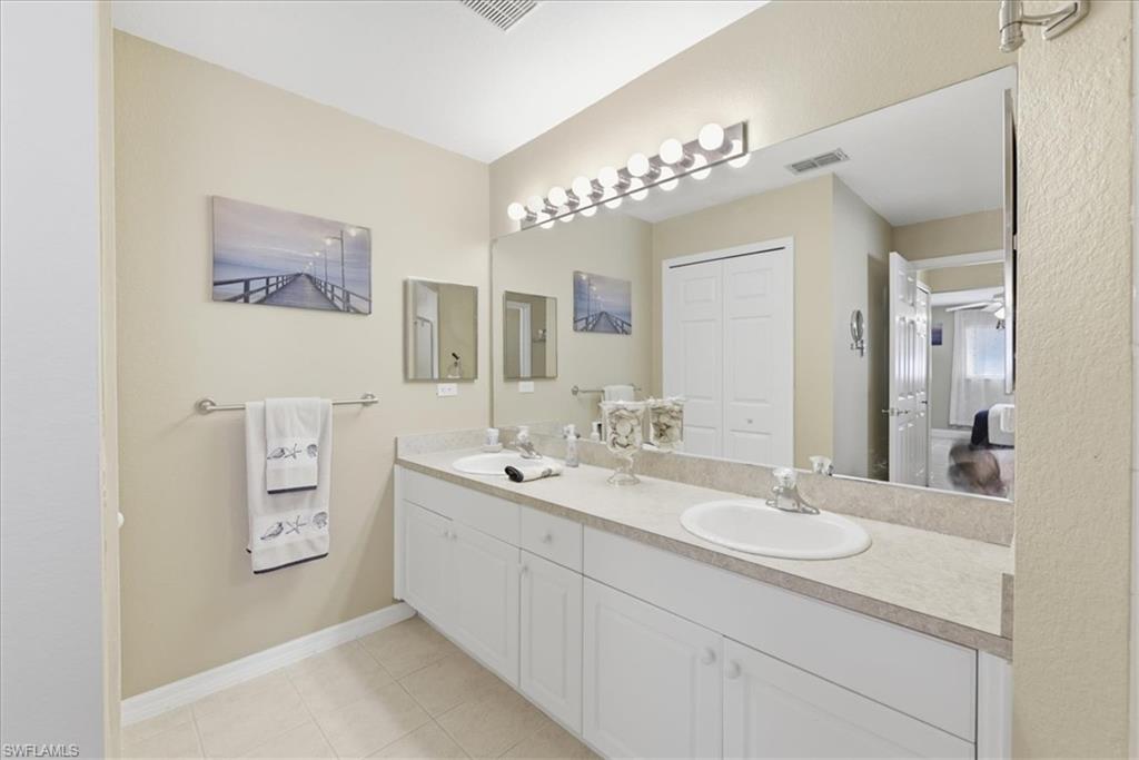 Full bath with double vanity, light tile patterned floors, and a closet